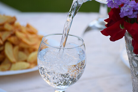 Mineralwasser wird in ein rundes Glas eingegossen