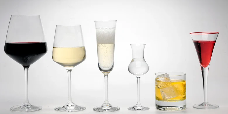 Sechs verschiedene Gläser mit verschiedenen Getränken: Rotwein, Weißwein, Sekt, Schnaps, Whisky on the Rocks und ein Cocktail. Alle Gläser stehen in einer Reihe vor weißem Hintergrund.